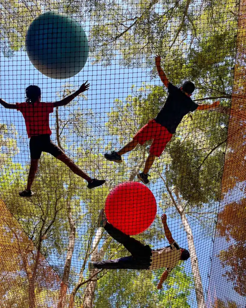 Participants défiant leur équilibre dans un filet suspendu au Parc Casse-Noisette, une activité immersive au cœur de la forêt. ​​